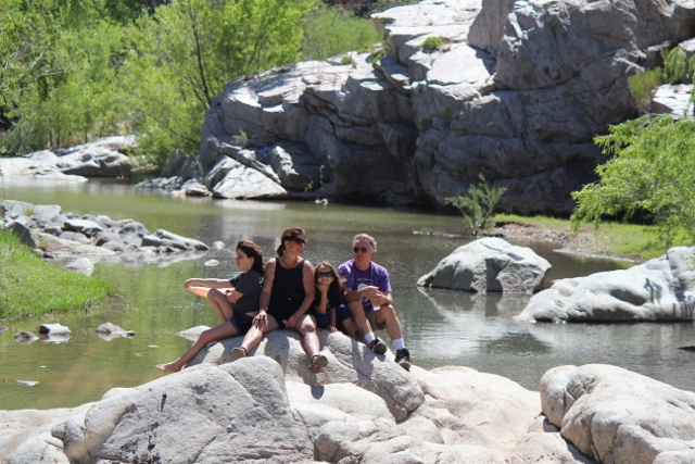 IMG_7953_-640x427- A group of people sitting on rocks near water.